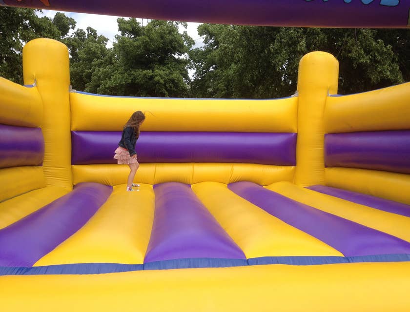 Un enfant sautant dans une structure gonflable jaune et violette.