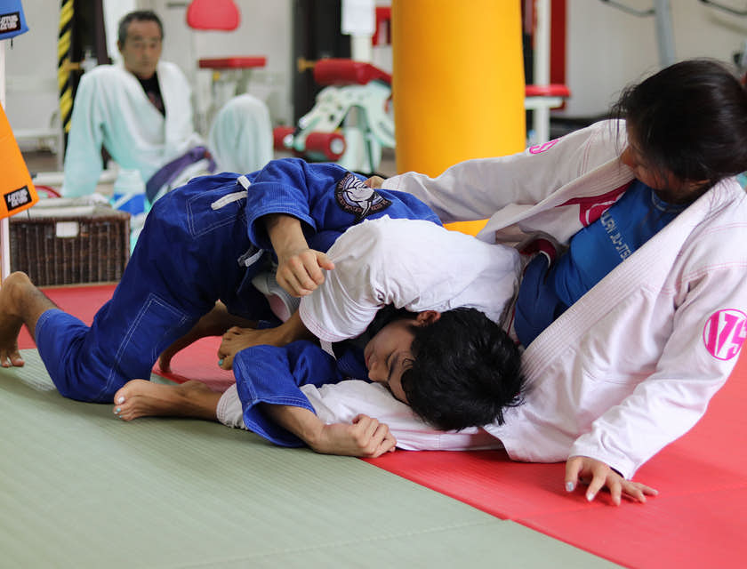 Homem e mulher lutando em uma academia de jiu-jitsu.