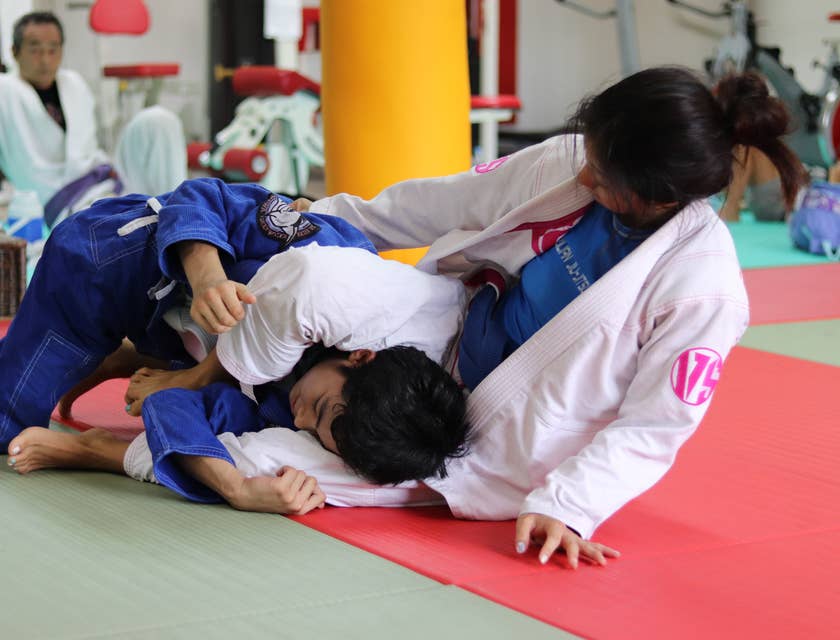 Homem e mulher lutando em uma academia de jiu-jitsu.