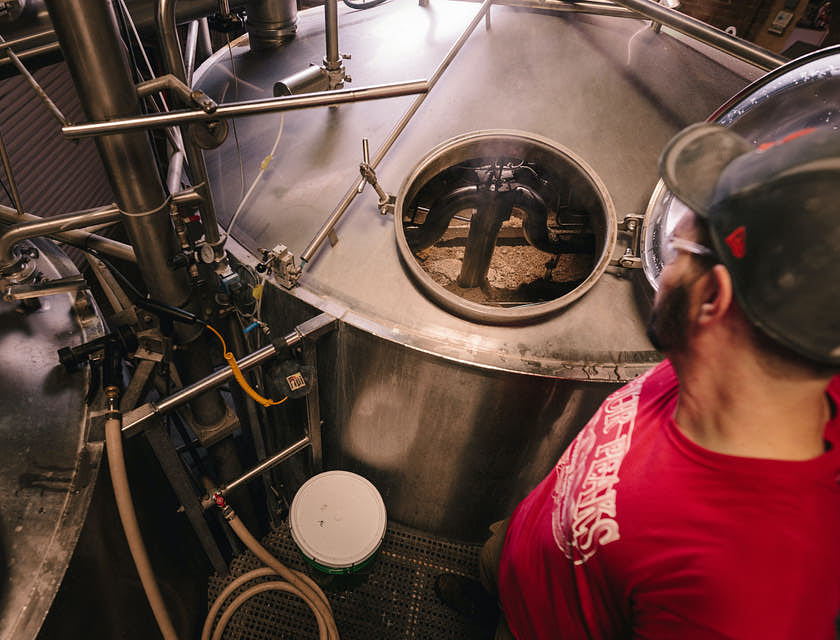 Un uomo che controlla un fermentatore per birra in un birrificio.