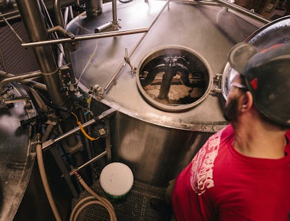 Un uomo che controlla un fermentatore per birra in un birrificio.