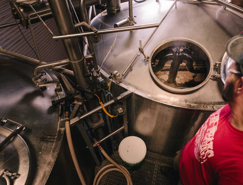 Un uomo che controlla un fermentatore per birra in un birrificio.