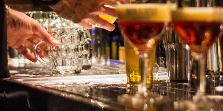 British pub with view of bar counter, beer taps and bartender pouring beer