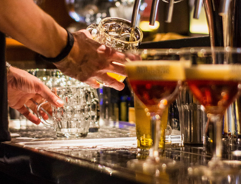 Il bancone di un British pub in cui c'è un barista che sta versando della birra in un boccale.