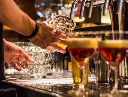 Il bancone di un British pub in cui c'è un barista che sta versando della birra in un boccale.