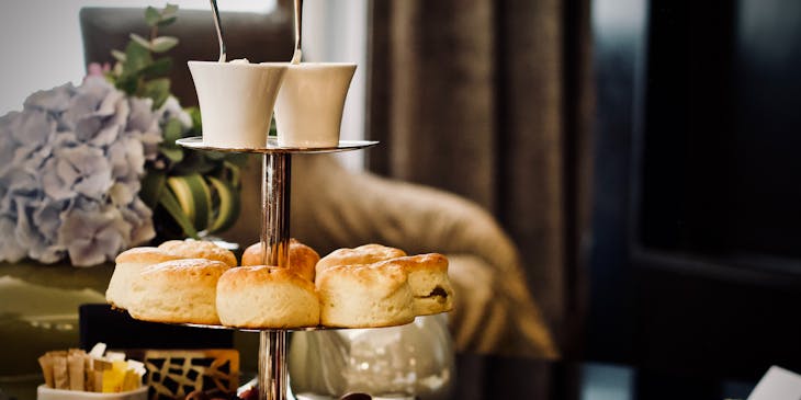 Set up for high tea with mini cakes, scones, and clotted cream at a British restaurant.