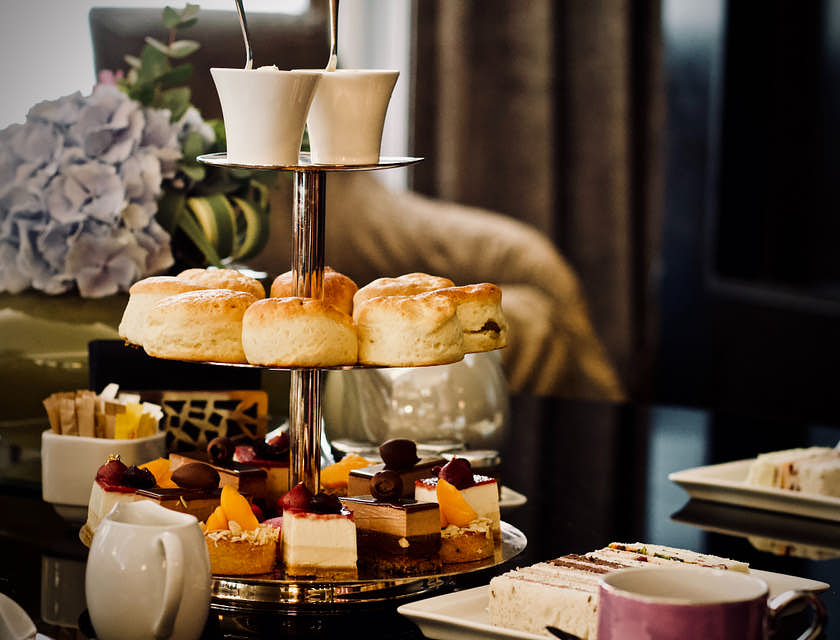 Une table mise pour le high-tea avec des mini-gâteaux, scones et crème caillée dans un restaurant britannique.