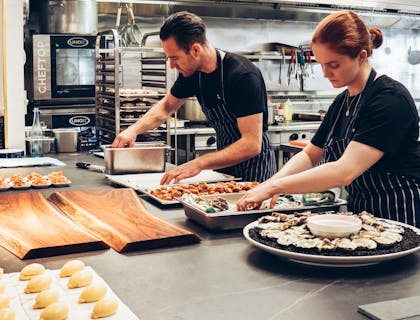 Homem e mulher preparando comida na cozinha de um restaurante de brunch.