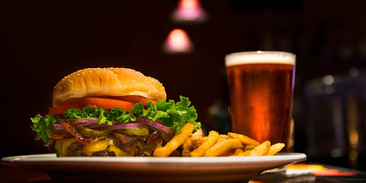 Plated burger and fries served with a glass of beer.