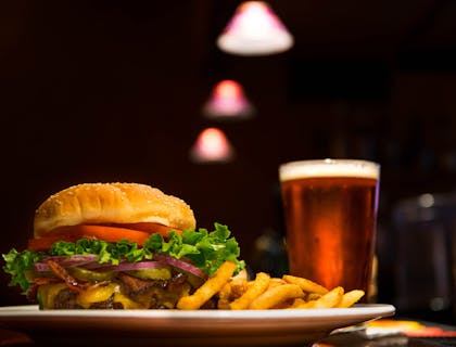 Un piatto con hamburger e patatine servito con un bicchiere di birra dentro un'hamburgeria.