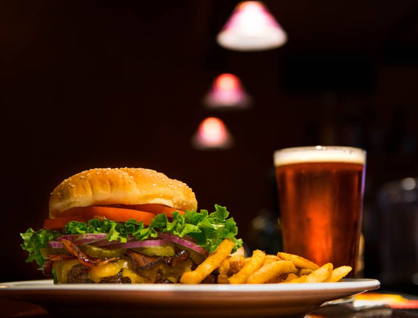 Plated burger and fries served with a glass of beer.