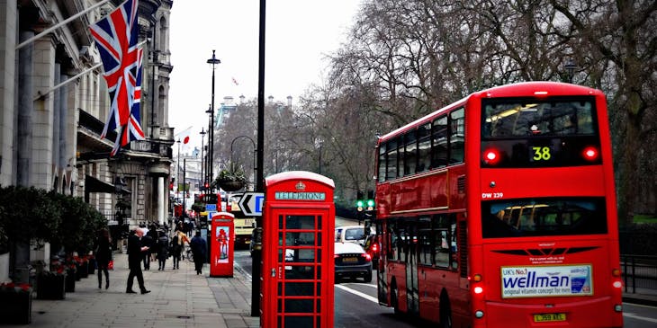 A red bus from a bus tour business riding on a road in London, England.