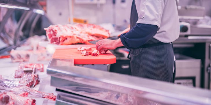 Butcher slicing raw meat into small sizes in a butcher business.
