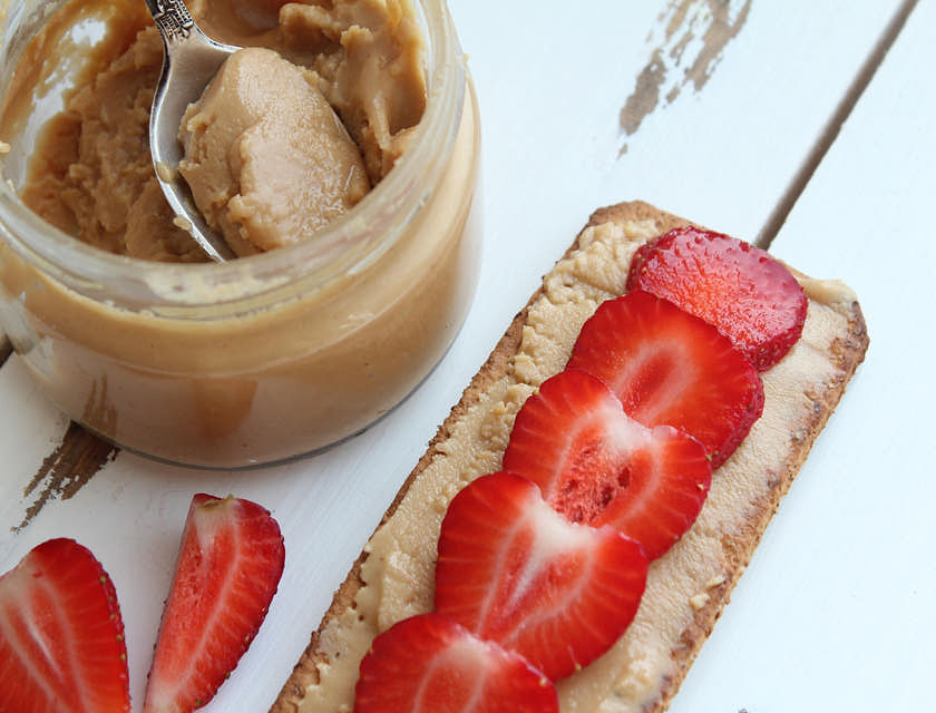 A jar of homemade butter and strawberries displayed on a white table.