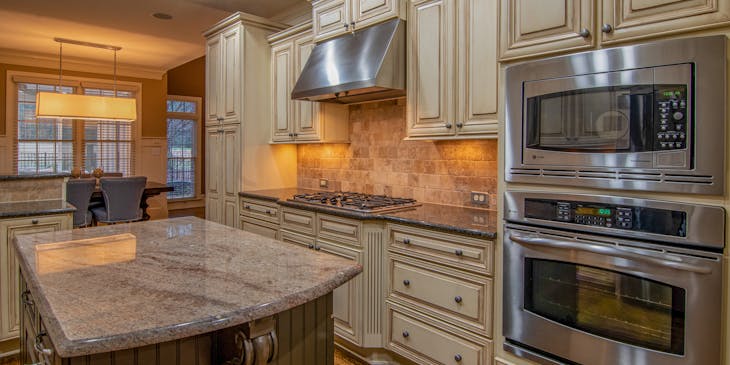 Light brown, wooden cabinetry in a kitchen with a silver oven.