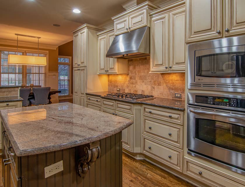 Light brown, wooden cabinetry in a kitchen with a silver oven.
