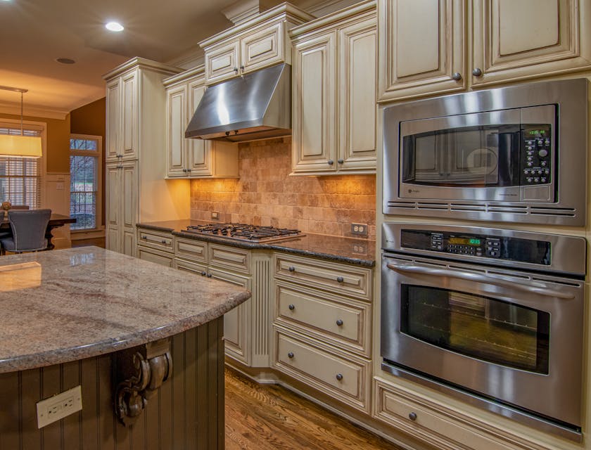 Light brown, wooden cabinetry in a kitchen with a silver oven.