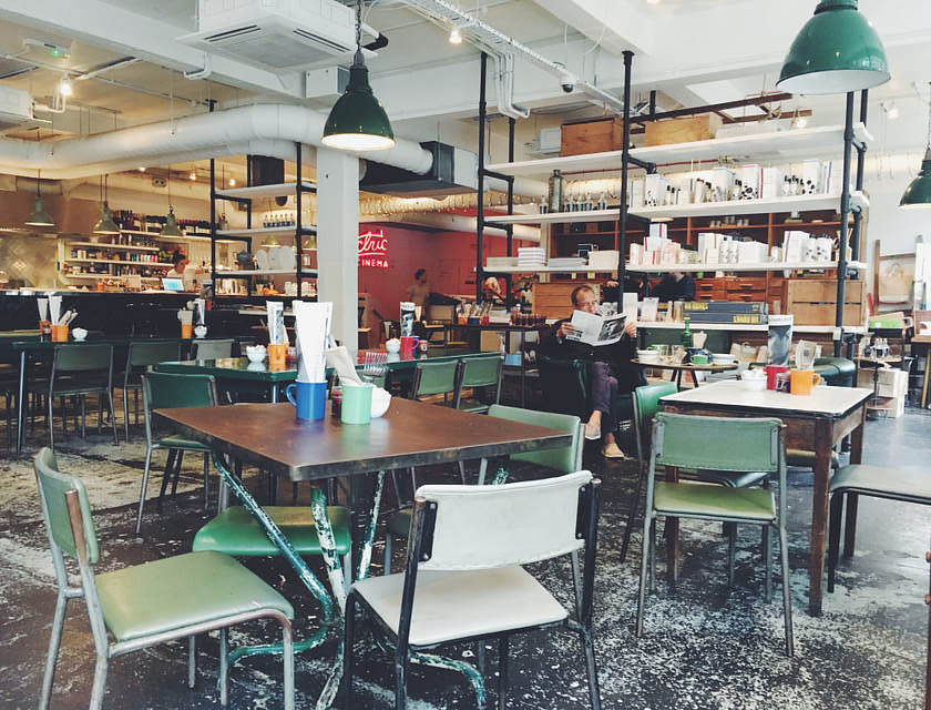 Une cafétéria avec des chaises blanches et vertes et des tables en bois.