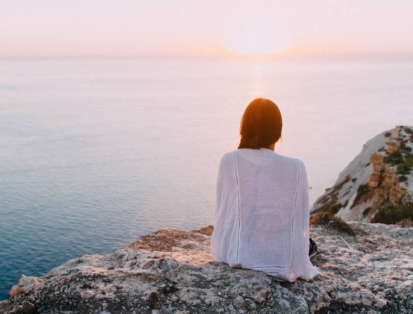 Uma mulher sentada em uma rocha com vista para um oceano relaxante.