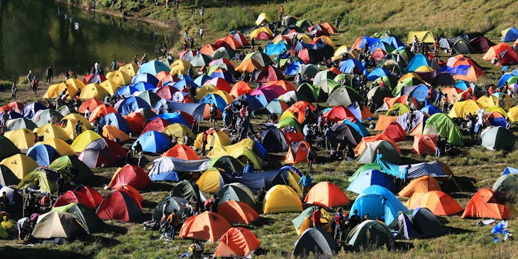 Pitched dome tents overlooking a mountain range in a campground.