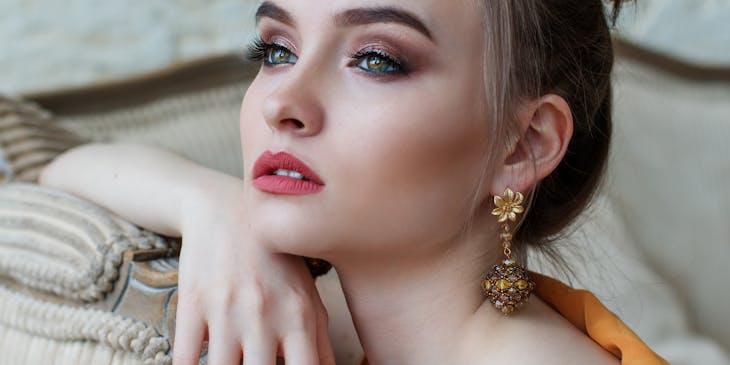 A captivating woman with pink lips and gold earrings.