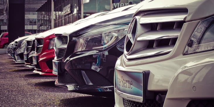 A row of cars parked in the showroom of a car business.