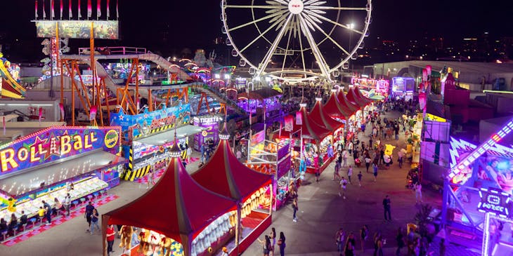 A carnival with a Ferris wheel and an assortment of stalls.