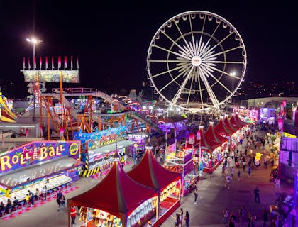 A carnival with a Ferris wheel and an assortment of stalls.