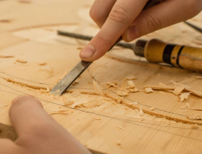 Carpintero cincelando un patrón en madera en un negocio de carpintería