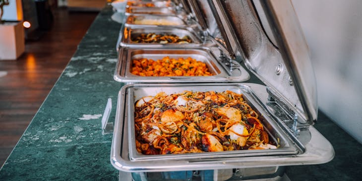An assortment of cooked food in food warmers at a catering business.