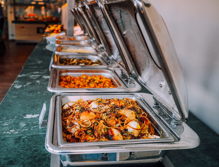 Un assortiment d'aliments cuits dans des réchauffeurs d'aliments dans une entreprise de restauration.