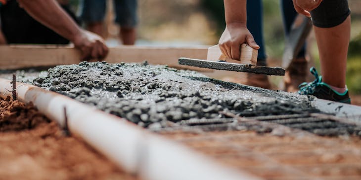 People laying a cement foundation for one of their cement business projects.