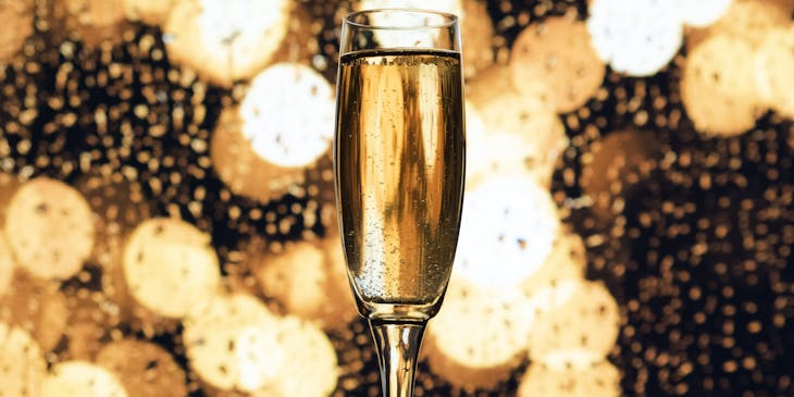 A champagne glass with gold lights in the background.