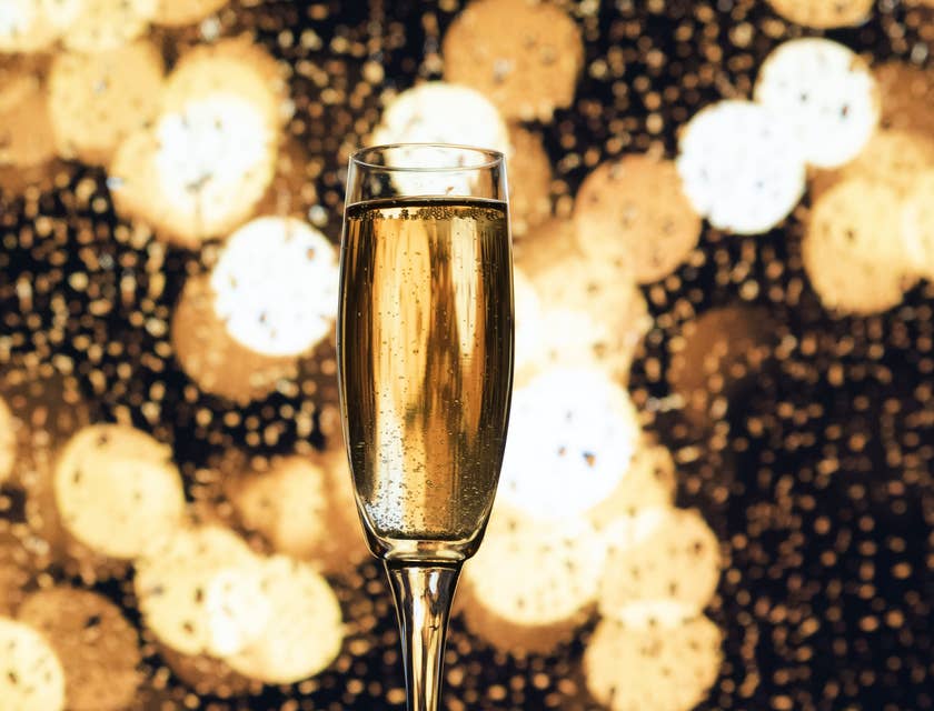 A champagne glass with gold lights in the background.