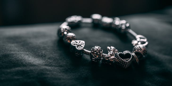 Silver charm bracelet on a dark background.
