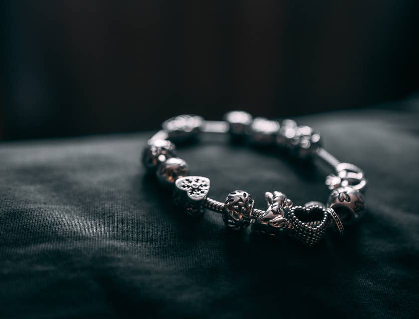 Un braccialetto in argento con dei ciondoli su sfondo nero.