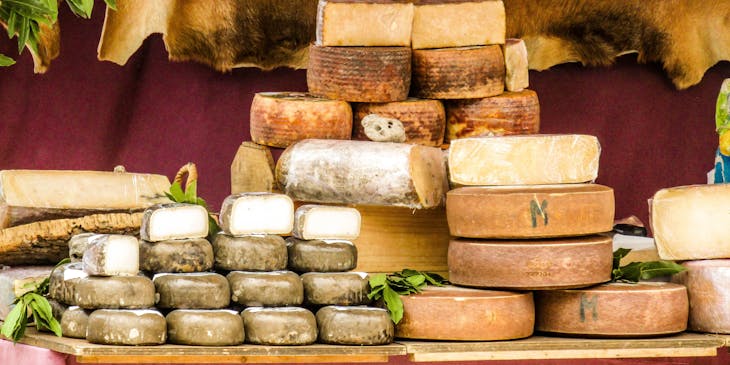 Stacks of cheese wheels on display in a cheese shop.