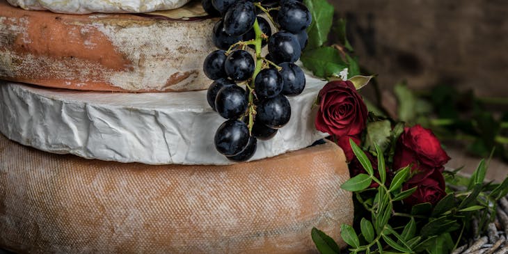 An assortment of cheeses displayed with grapes in a cheese tasting class.
