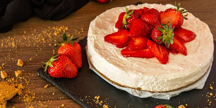 cheesecake topped with strawberries on wooden table