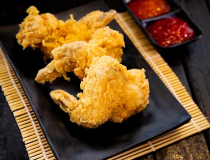 Tres piezas de alitas fritas sobre un plato negro.