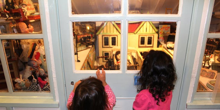 Two girls looking at a doll house display at a children's museum.