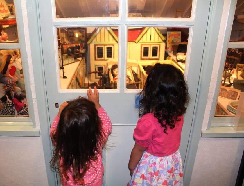 Two girls looking at a doll house display at a children's museum.
