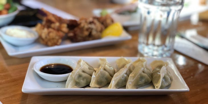 A plate of five dumplings served with a glass of water at a Chinese restaurant.