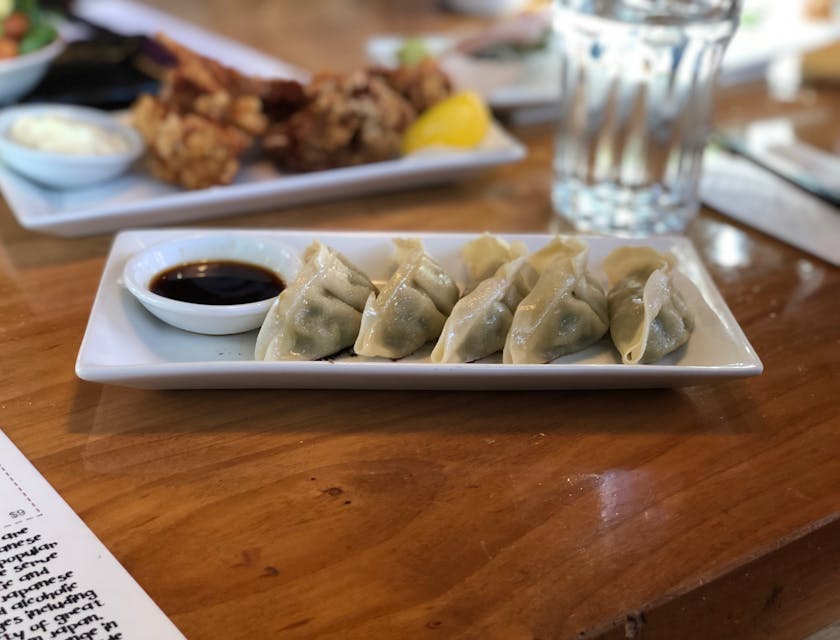 Plato de cinco dumplings servidas con un vaso de agua en un restaurante chino.