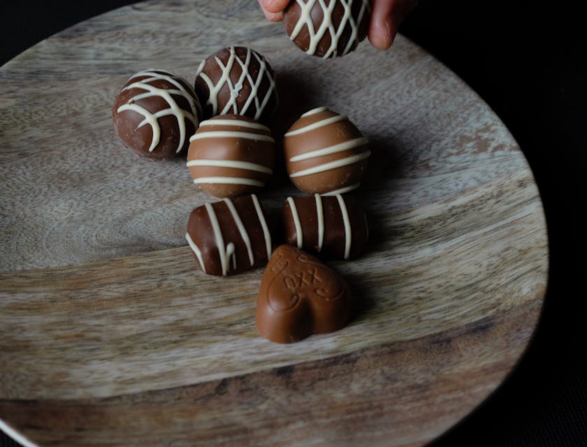 Una mano eligiendo una trufa de chocolate de un plato en un negocio de chocolate.