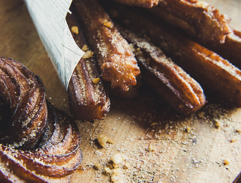 Dei churros ricoperti di zucchero e cannella sistemati sopra un bancone.