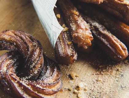 Des churros saupoudrés de sucre sur une planche à découper en bois.
