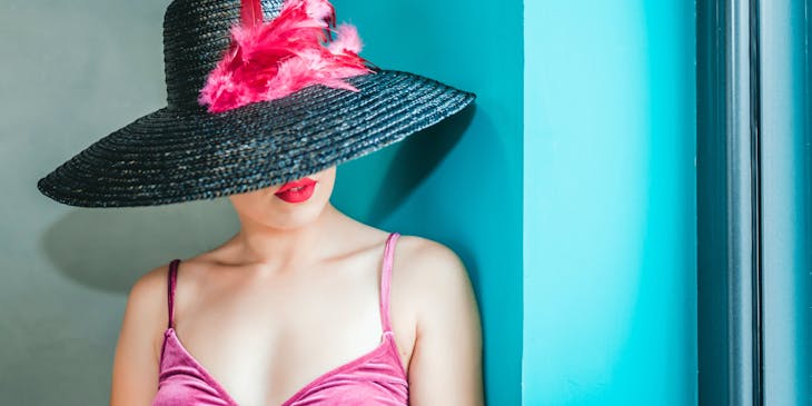 A woman wearing a wide-brimmed hat decorated with pink feathers.