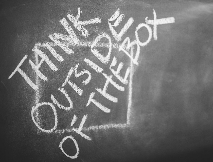 Un dessin intelligent à la craie représentant un carré et les mots "think outside of the box" écrits dessus.