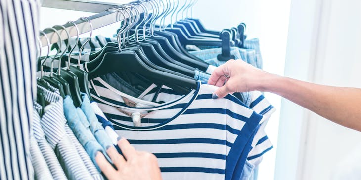Woman browsing through shirts at a clothing business.